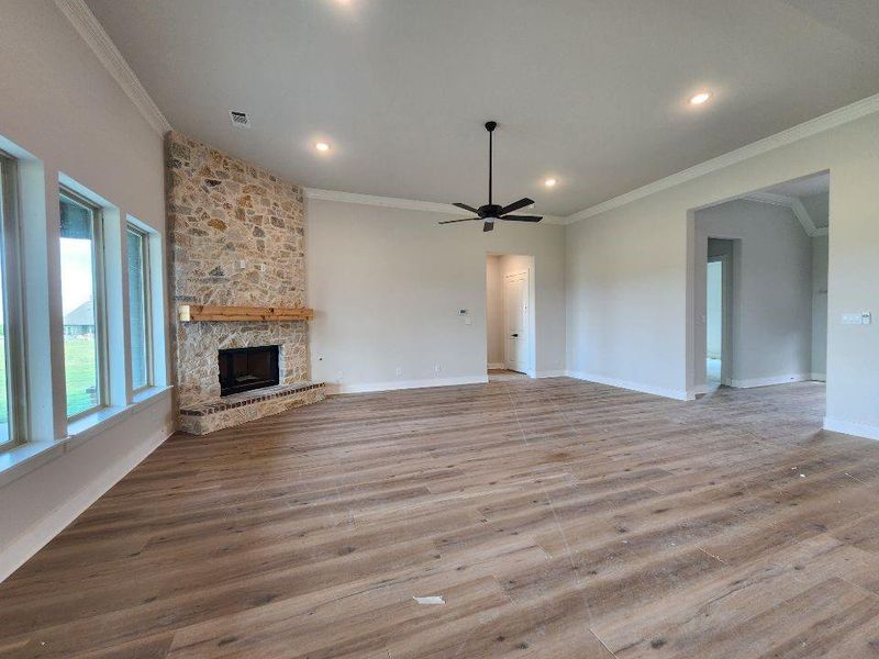 Spacious living area featuring a floor-to-ceiling stone fireplace with a wood mantle, wood-finish flooring, recessed lighting, and a ceiling fan