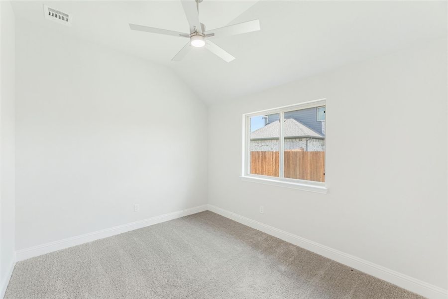Empty bedroom with vaulted ceiling, ceiling fan, carpet flooring, and a single window Empty bedroom with vaulted ceiling, ceiling fan, carpet flooring, and a single window