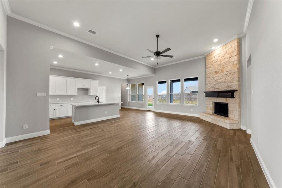 Unfurnished living room with ceiling fan, ornamental molding, and a fireplace