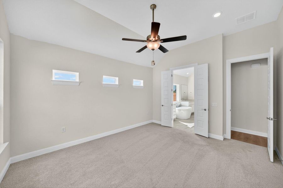Unfurnished bedroom featuring light colored carpet, lofted ceiling, ensuite bath, a ceiling fan, and recessed lighting Unfurnished bedroom featuring light colored carpet, lofted ceiling, ensuite bath, a ceiling fan, and recessed lighting