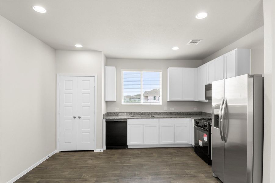 Kitchen featuring black appliances, white cabinets, dark wood-style flooring, recessed lighting, and dark stone counters Kitchen featuring black appliances, white cabinets, dark wood-style flooring, recessed lighting, and dark stone counters