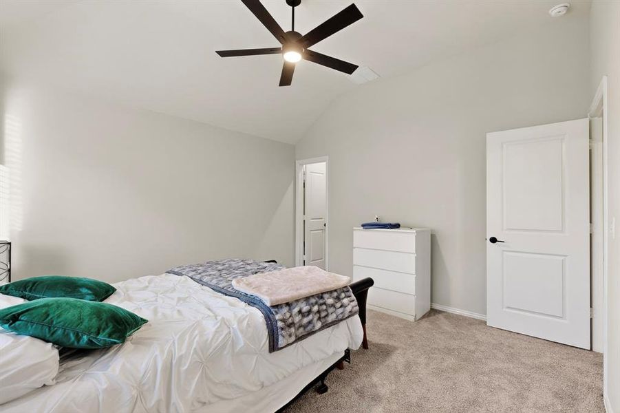 Bedroom with vaulted ceiling, light colored carpet, and a ceiling fan Bedroom with vaulted ceiling, light colored carpet, and a ceiling fan
