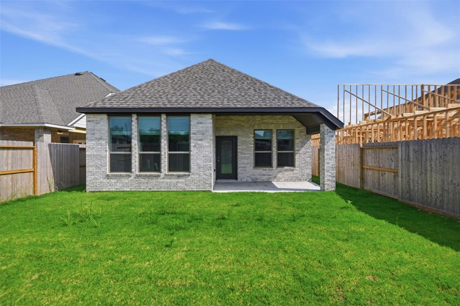 Charming brick home with a spacious backyard, featuring a covered patio perfect for outdoor relaxation and entertainment.