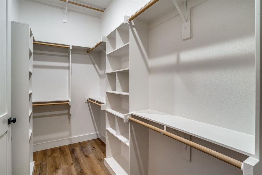 Walk in closet with light hardwood / wood-style flooring