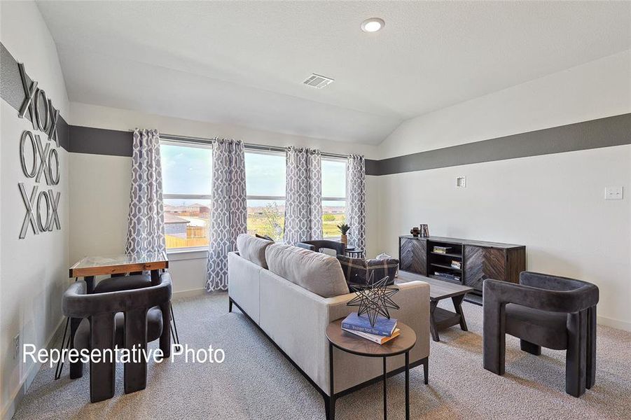 Carpeted living space featuring vaulted ceilings, recessed lighting, and a series of three windows