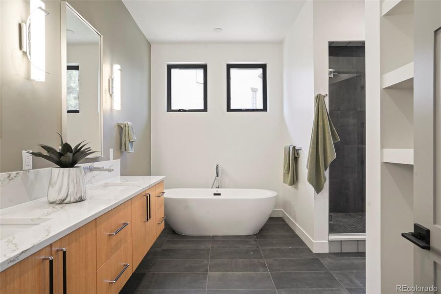 Primary suite bath offers soaking tub, gracious counter space, large shower and connects to walk-in closet and laundry