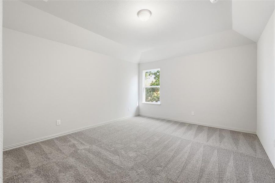 Carpeted empty room with vaulted ceiling and baseboards