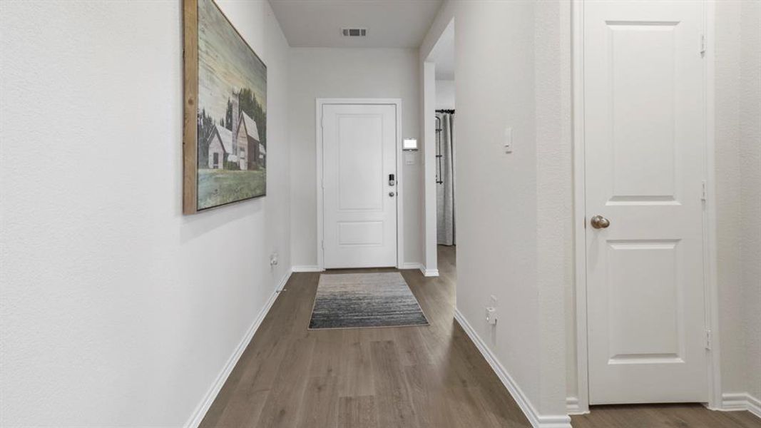 Entryway featuring wood-finish flooring, white baseboards, and a paneled interior door