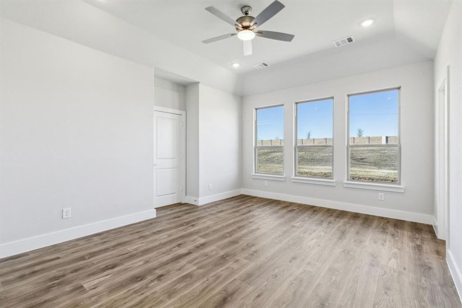 Empty room with ceiling fan, lofted ceiling, and light wood-type flooring