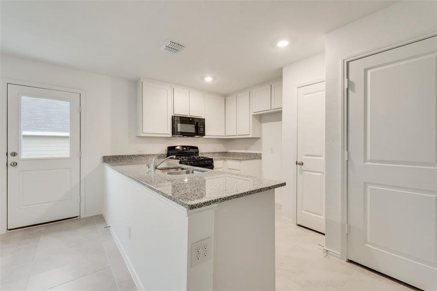 Kitchen featuring white cabinetry, black appliances, light tile patterned floors, and kitchen peninsula