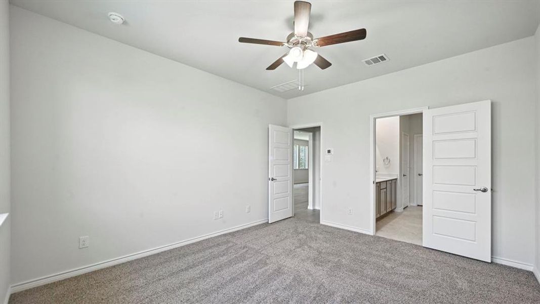 Unfurnished bedroom with light colored carpet, connected bathroom, and ceiling fan Unfurnished bedroom with light colored carpet, connected bathroom, and ceiling fan