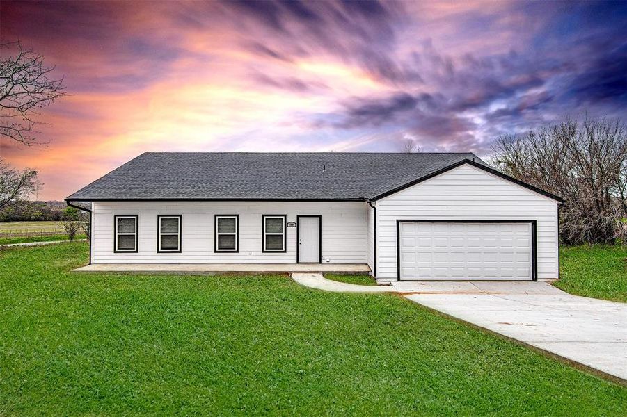 View of front of house featuring a garage and a yard