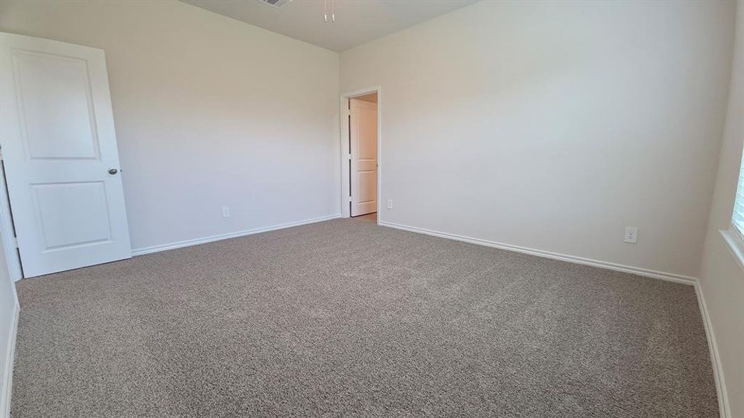 Spacious room featuring neutral carpeting, white walls, and white trim Spacious room featuring neutral carpeting, white walls, and white trim