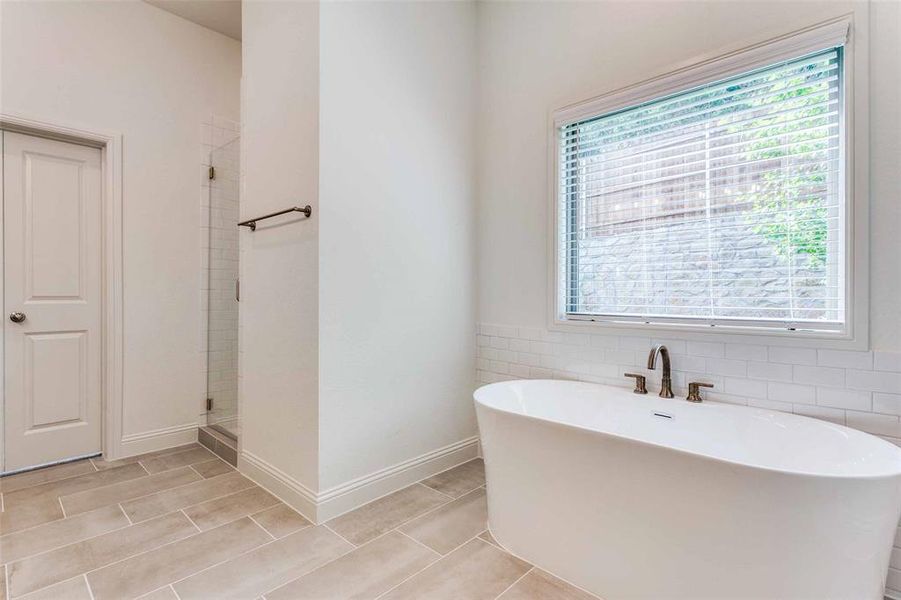 Bathroom with a freestanding bath, a shower stall, and baseboards Bathroom with a freestanding bath, a shower stall, and baseboards