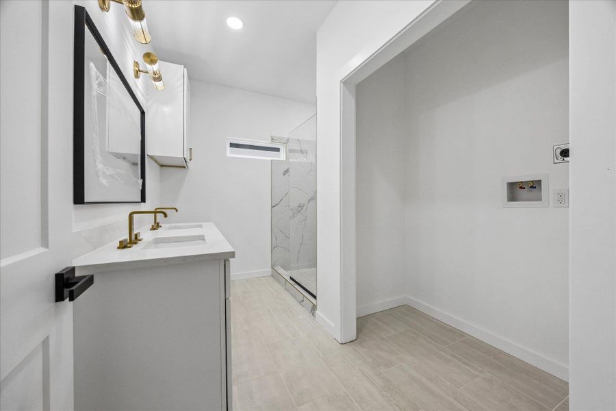 A well-lit bathroom with a double vanity and a convenient laundry area. A well-lit bathroom with a double vanity and a convenient laundry area.