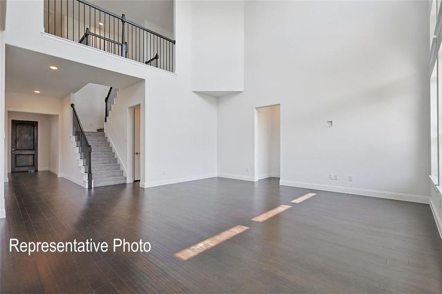 Unfurnished living room with hardwood / wood-style flooring and a towering ceiling