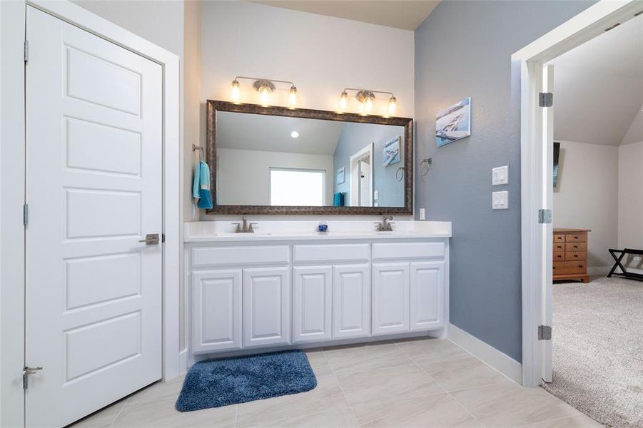 Full bath featuring double vanity, light tile patterned flooring, and light carpet