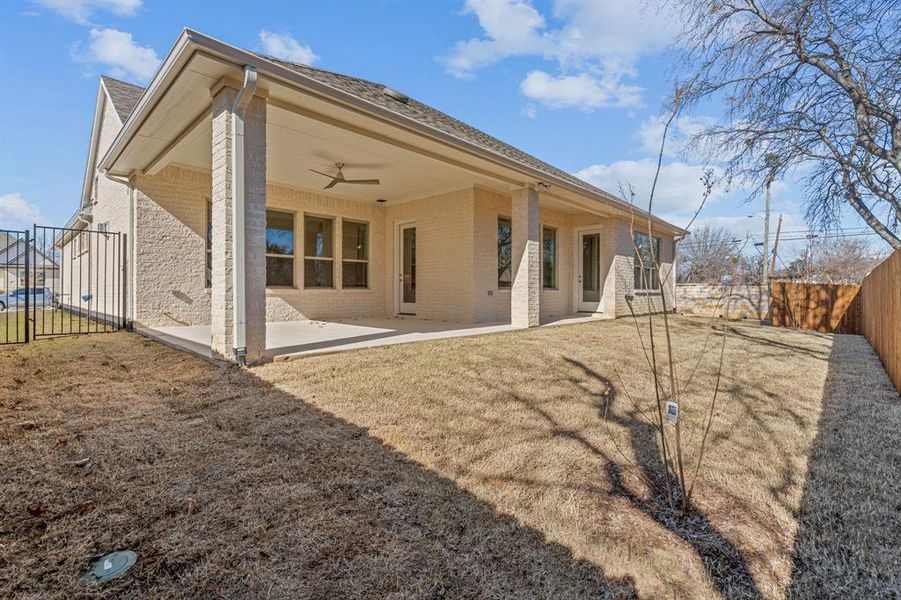 Rear view of property featuring ceiling fan, a patio, and a lawn