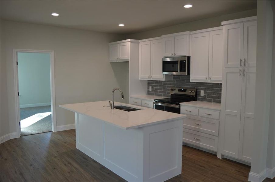 Kitchen featuring stainless steel appliances, sink, a center island with sink, dark hardwood / wood-style floors, and white cabinetry