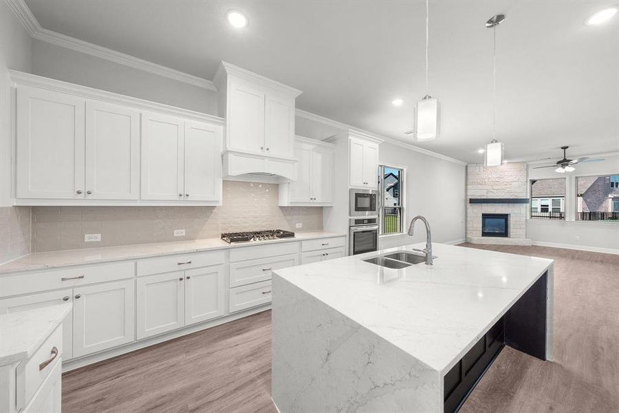 Kitchen featuring crown molding, tasteful backsplash, white cabinets, an island with sink, and light wood-style floors