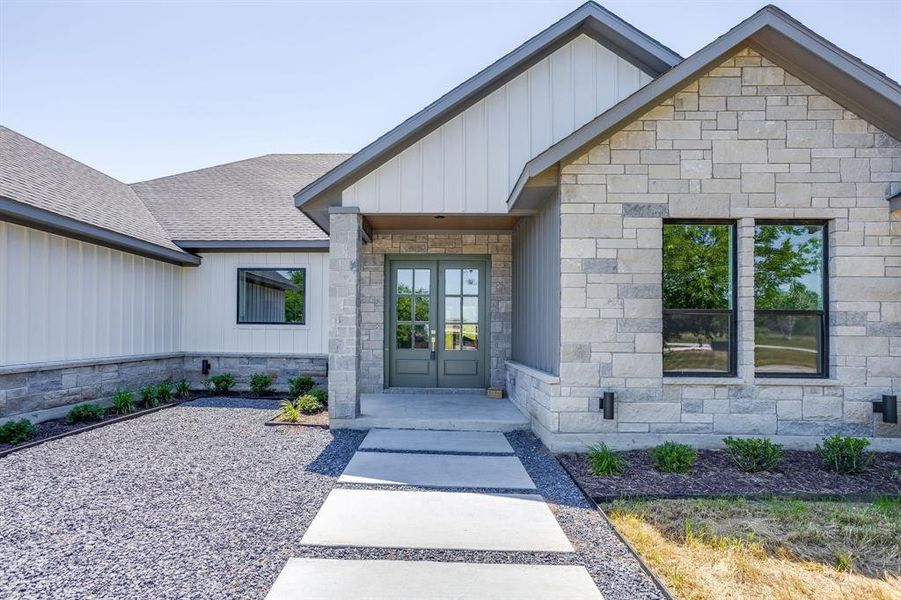 Stone and board-and-batten exterior with a dark gray shingle roof