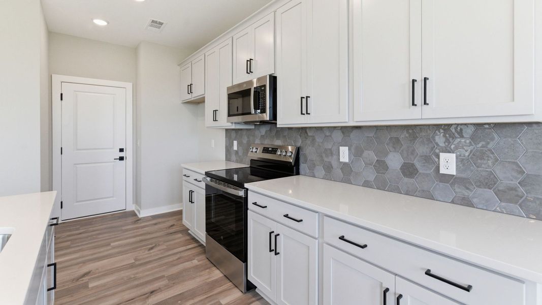 Kitchen with tile backsplash, pendant lighting, and quartz countertops Kitchen with tile backsplash, pendant lighting, and quartz countertops