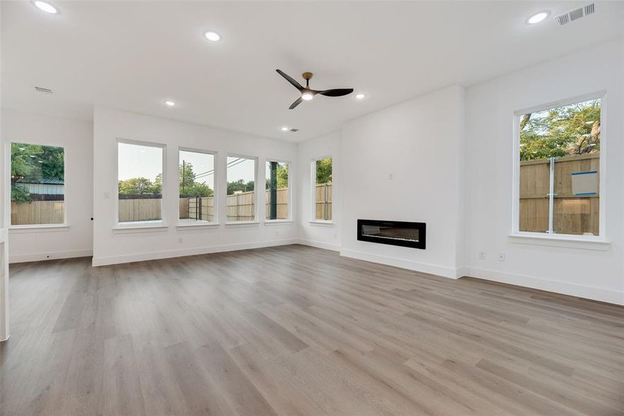 Unfurnished living room with recessed lighting, light wood-style flooring, a glass covered fireplace, and ceiling fan