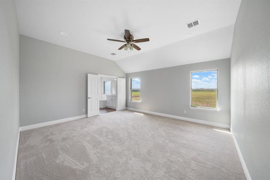 Carpeted empty room with ceiling fan and lofted ceiling