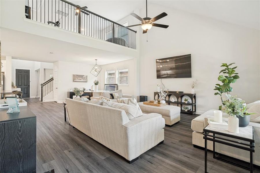 Spacious living area featuring vaulted ceilings, wood-finish flooring, and a second-story overlook with black metal railings