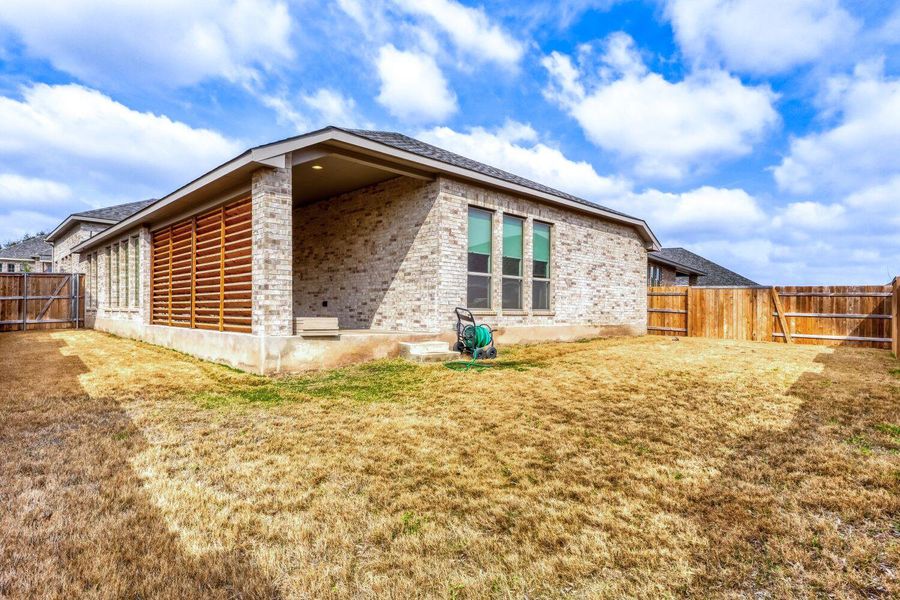 View of property exterior featuring a fenced backyard, brick siding, and a patio area