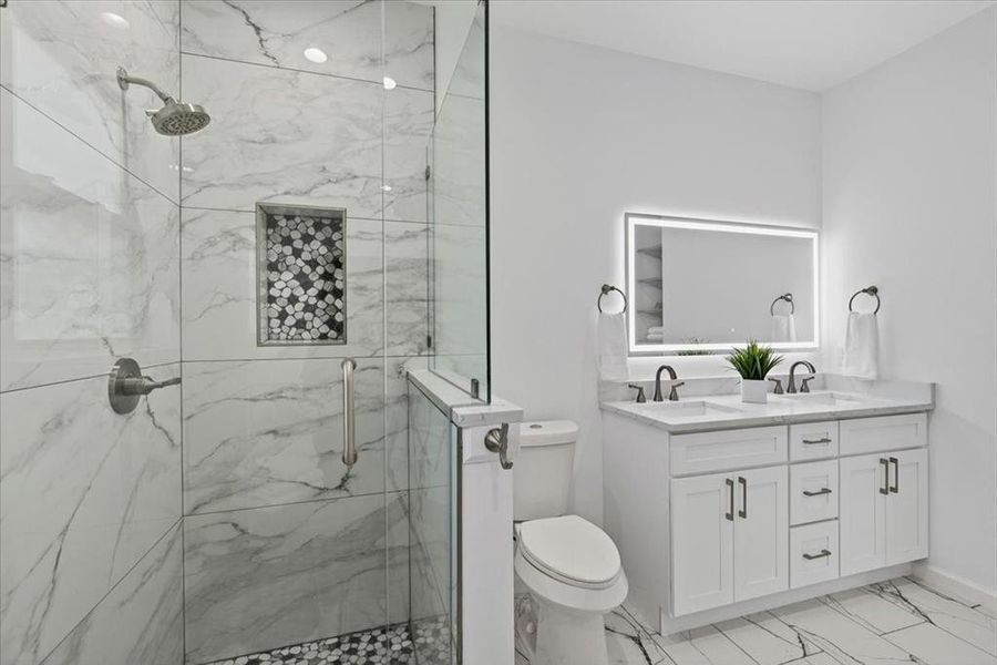 Contemporary bathroom featuring a spacious glass-enclosed shower with large format marble-look tile walls and a pebble-tiled shower niche