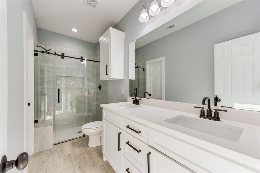 Bathroom with vanity, an enclosed shower, and toilet