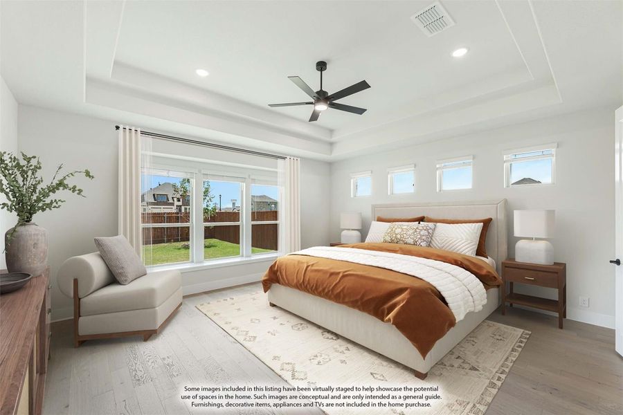 Master bedroom with tray ceiling, ceiling fan, hardwood floors, and large windows with backyard view Master bedroom with tray ceiling, ceiling fan, hardwood floors, and large windows with backyard view