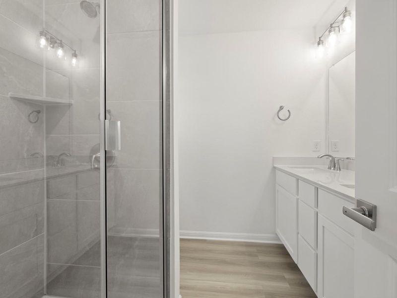 Modern bathroom featuring a spacious glass-enclosed shower and a sleek vanity with double sinks.