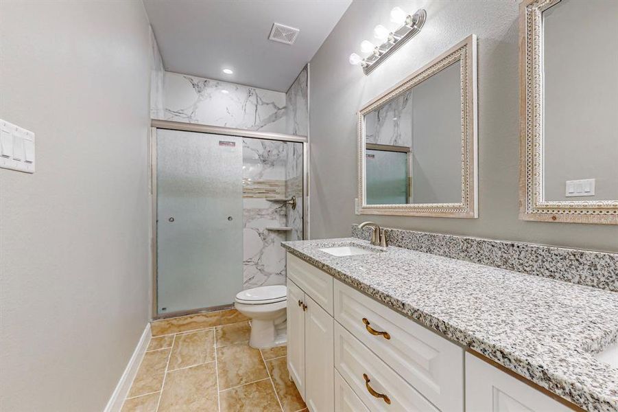 Bathroom with tile patterned floors, walk in shower, vanity, and toilet