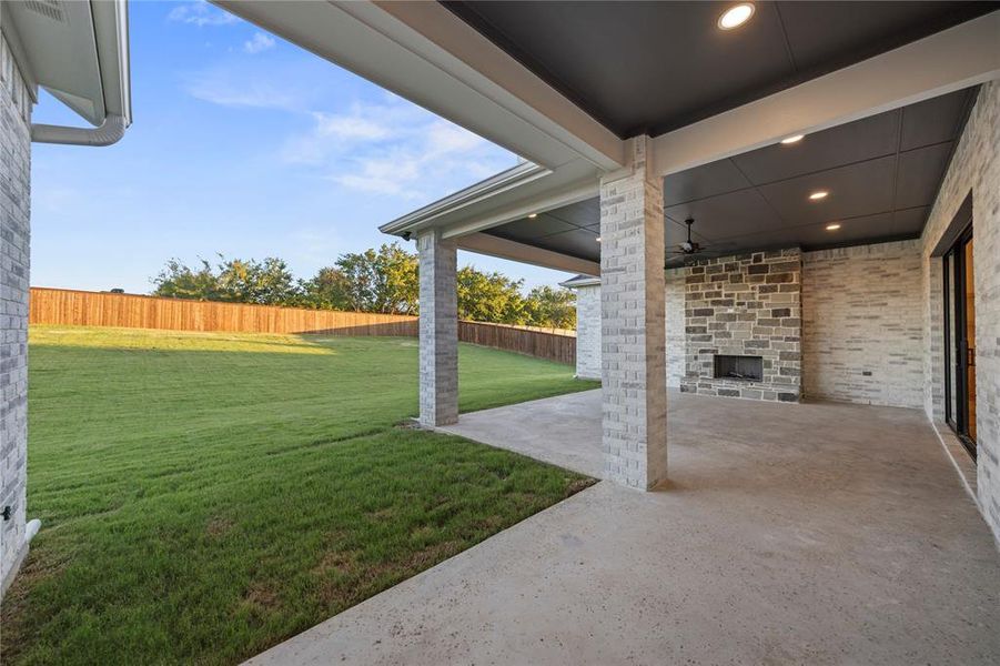 Covered patio featuring recessed lighting, a ceiling fan, and a stone-clad outdoor fireplace