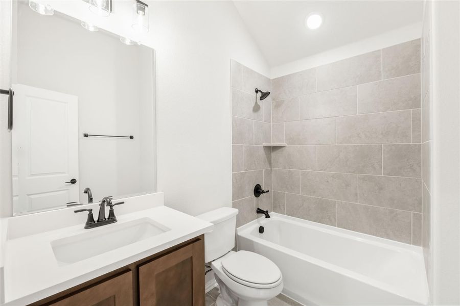 Bathroom with single vanity, white countertop, tub-shower combo with beige tile surround, and dark bronze fixtures