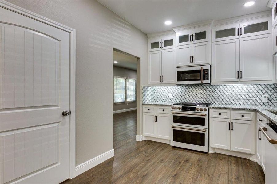 Kitchen with glass insert cabinets, double oven range, white cabinets, and recessed lighting