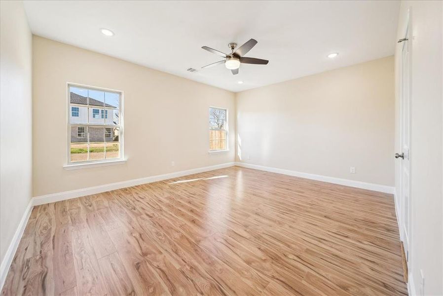 Empty room with ceiling fan and light hardwood / wood-style floors