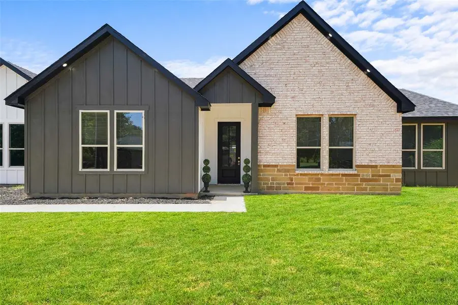Contemporary exterior featuring a combination of light-colored brick, vertical dark siding, and a stone accent foundation Contemporary exterior featuring a combination of light-colored brick, vertical dark siding, and a stone accent foundation