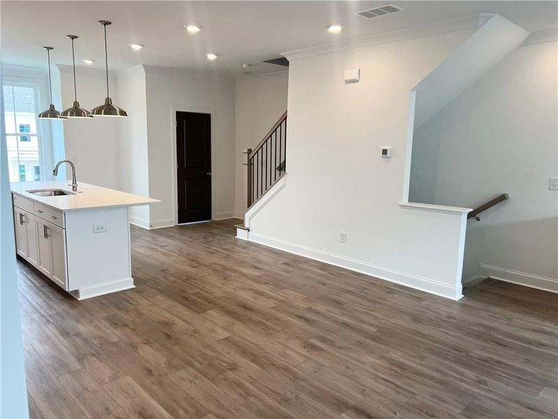 Kitchen with dark wood-style flooring, open floor plan, an island with sink, light countertops, and recessed lighting