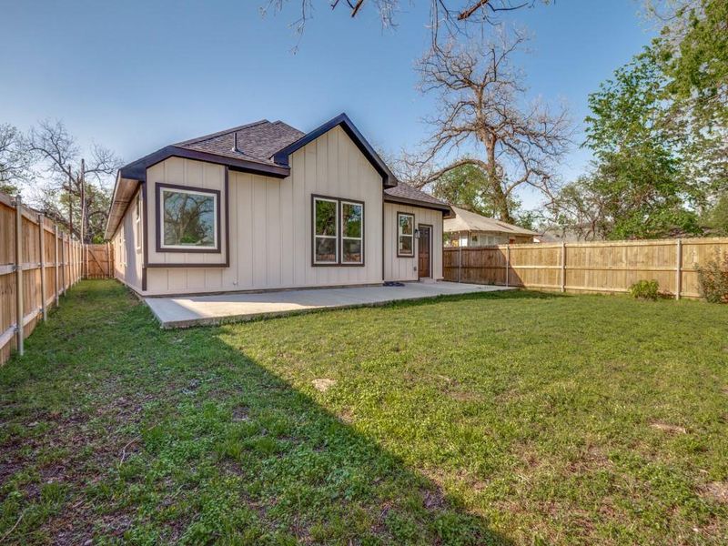Rear view of house featuring a yard, a fenced backyard, a patio, and board and batten siding Rear view of house featuring a yard, a fenced backyard, a patio, and board and batten siding