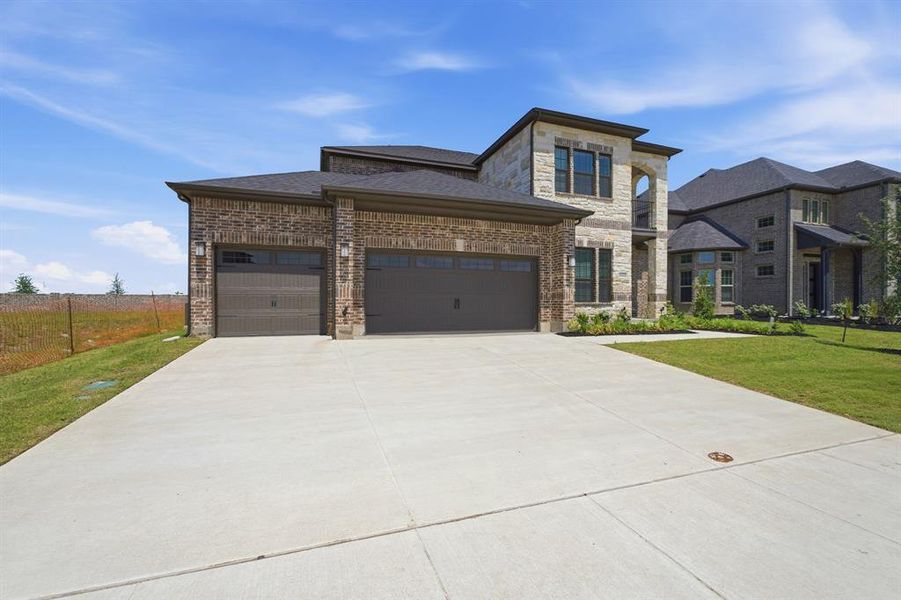 Stately brick and stone facade featuring a multi-car garage with dark wood-finish doors Stately brick and stone facade featuring a multi-car garage with dark wood-finish doors