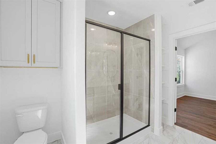 Full bathroom featuring visible vents, toilet, marble finish floor, a stall shower, and baseboards