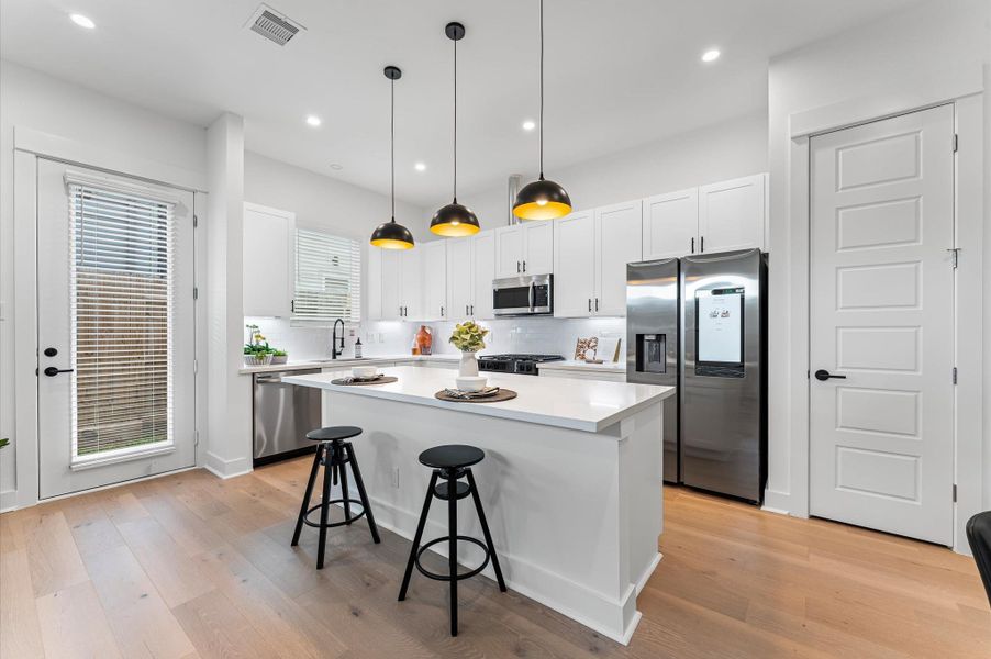 This centrally positioned kitchen island serves as a stylish anchor within the open-concept layout, offering clear sightlines to the dining area, living space, and the backyard beyond. Its placement encourages seamless interaction, whether prepping meals or entertaining guests, while natural light pours in through the nearby windows. The island’s sleek design and functional surface make it a hub of activity, framed by elegant finishes tying together comfort and sophistication.