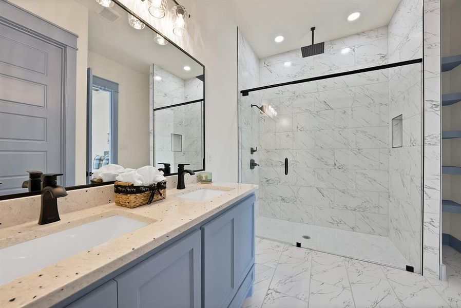 Full bath with light marble finish flooring, double vanity, a marble finish shower, and recessed lighting