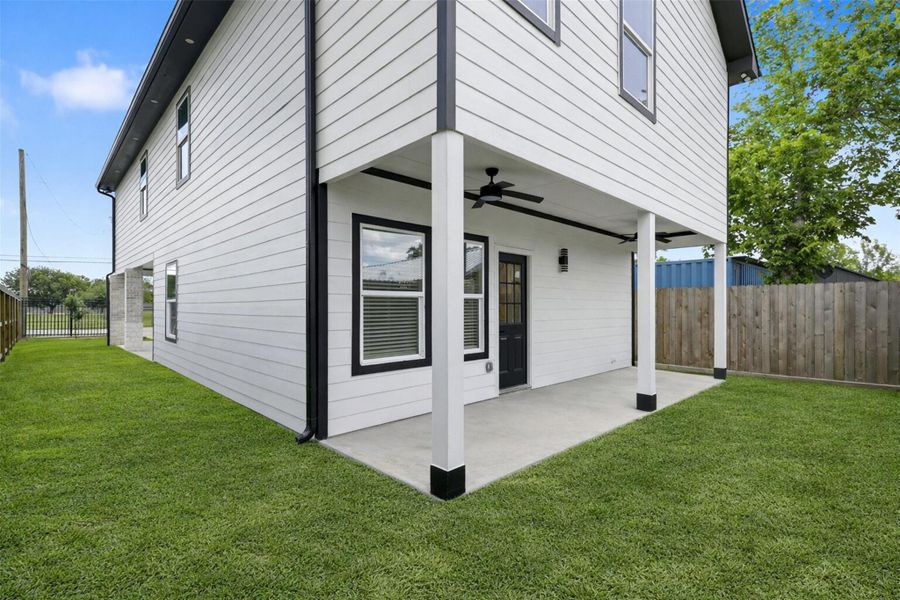 Spacious backyard with green lawn, covered patio, and privacy fence — great for outdoor relaxation.