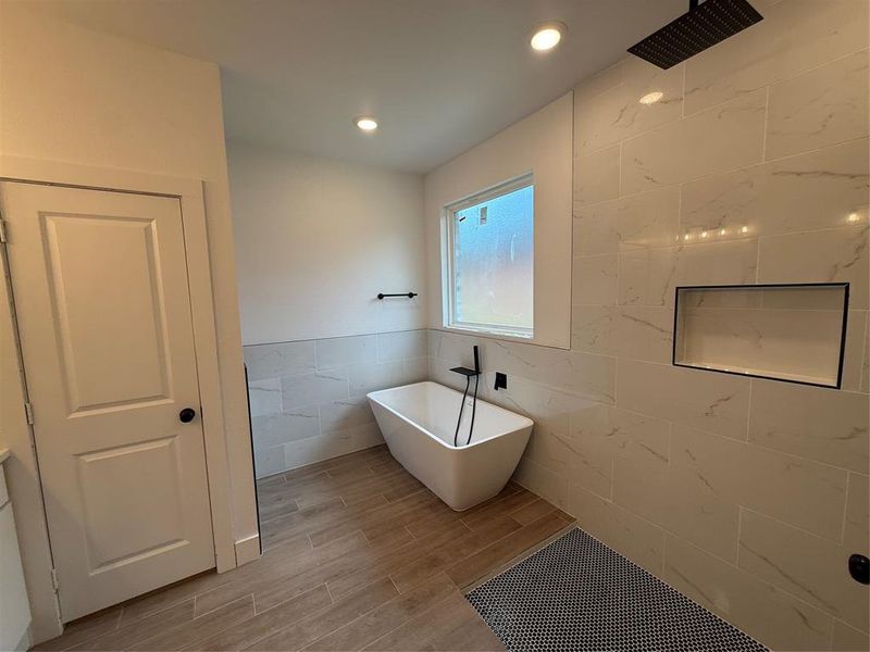 Bathroom with tile walls, a soaking tub, wood finish floors, a tile shower, and recessed lighting Bathroom with tile walls, a soaking tub, wood finish floors, a tile shower, and recessed lighting