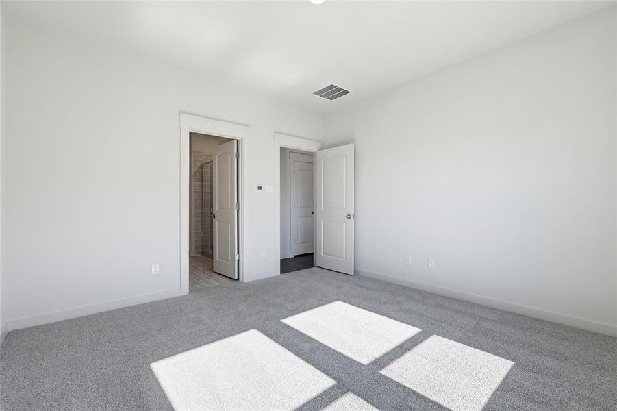 Spacious room featuring light gray carpeting, neutral wall finishes, and two white panel doors