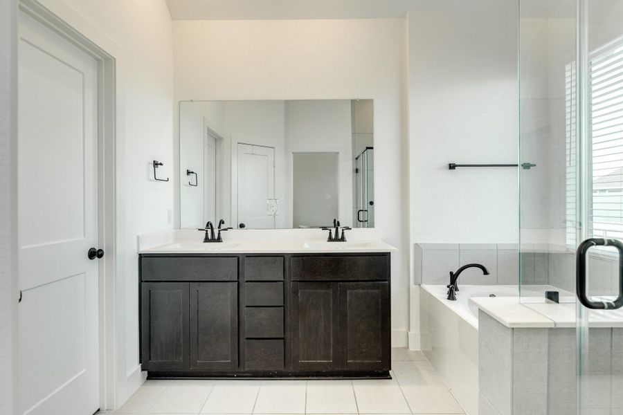 Primary bath features double vanities with quartz countertops, a soaking tub, and a glass walk-in shower.